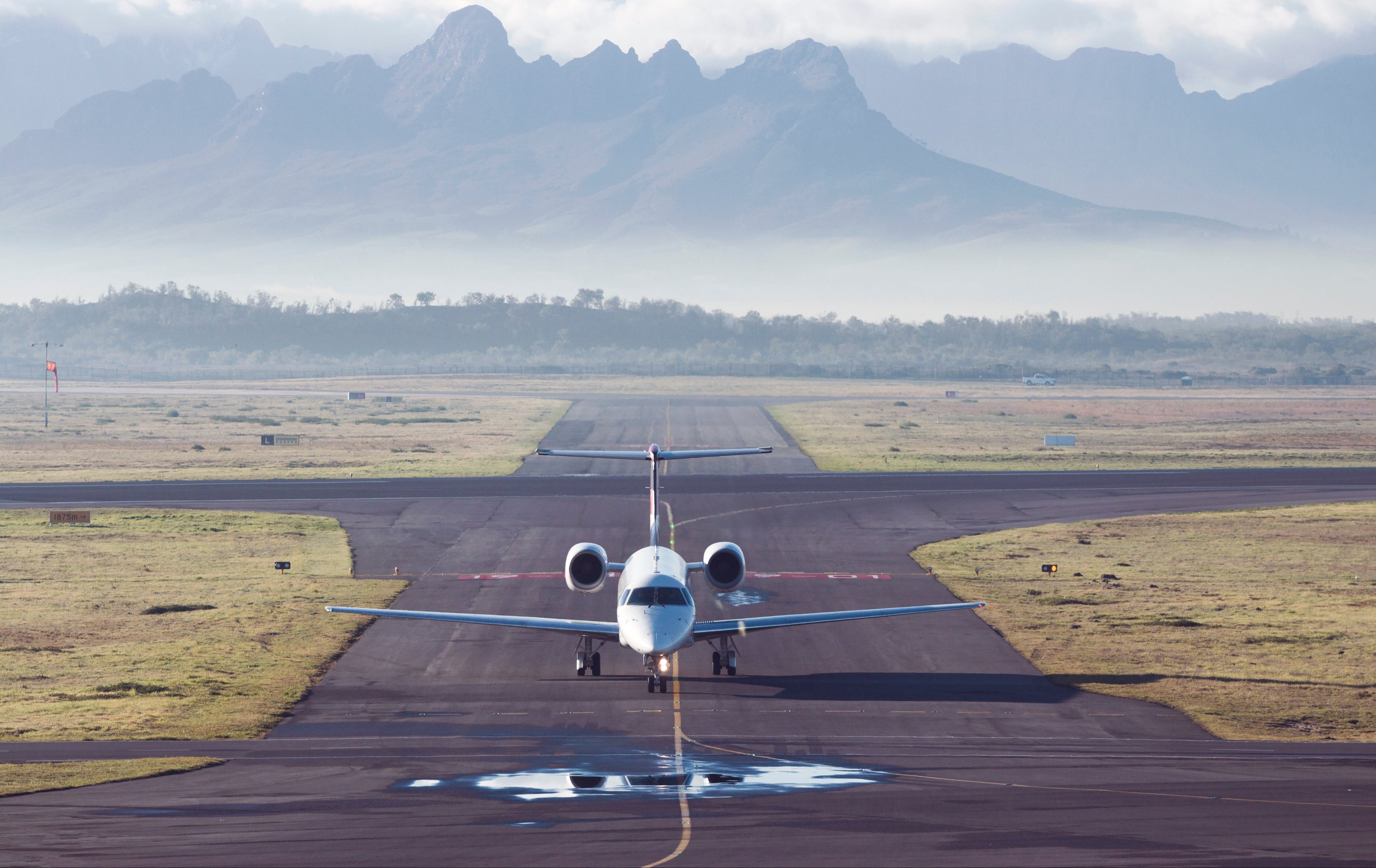 Private jet on a runway with mountains in the background
